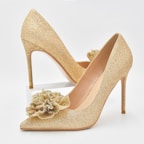 Elegant women’s heels in soft pastel shades placed on a marble surface with delicate floral accents