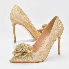Close-up of a pair of glossy black stiletto heels with delicate gold accents on a white background.
