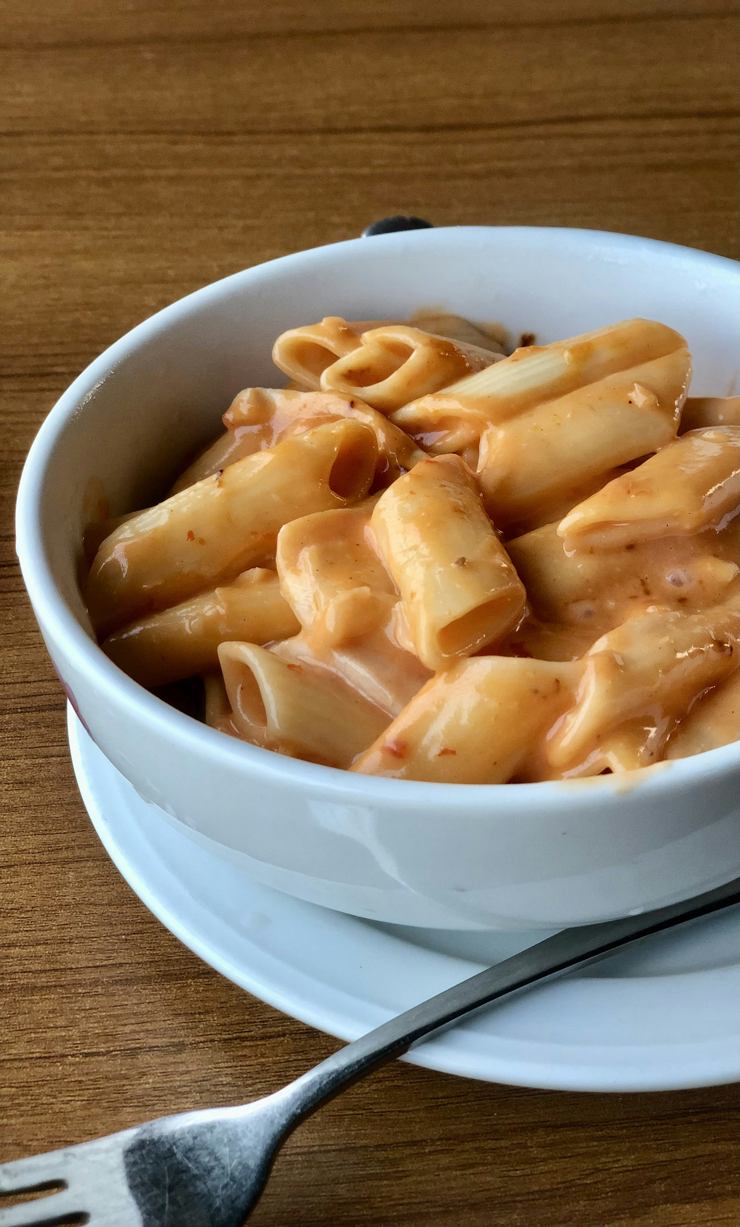 Creamy penne pasta with garlic cream sauce and fresh parmesan in a white bowl