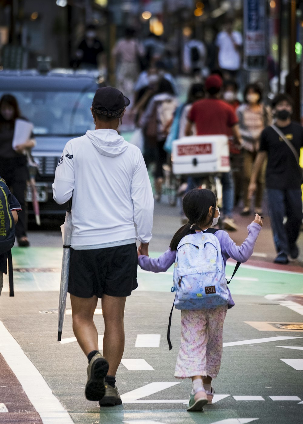 Una persona y una niña caminando por una calle