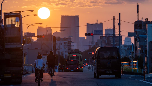 Urban cyclist riding through a bustling city street at sunset.