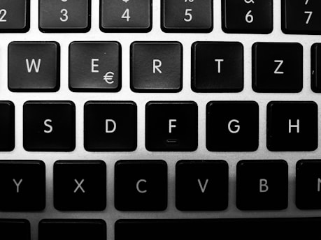 A close-up view of a black and white keyboard, featuring keys with white letters, symbols, and numbers on top of dark keys on a silver frame.