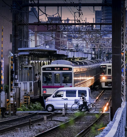 a person riding a bicycle next to a couple of trains on the tracks
