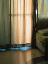 A peaceful room with soft sage green walls and golden light filtering through sheer curtains.