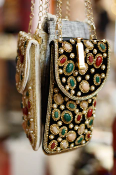 Luxurious potli bags in deep peacock green and gold embroidery displayed on a white surface