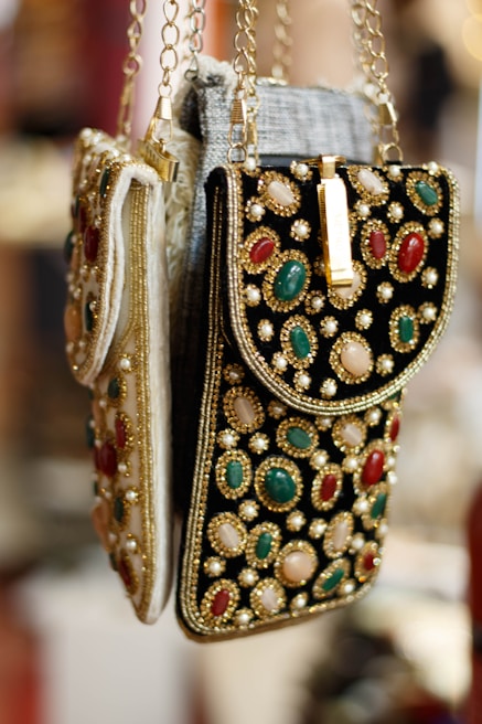Elegant leather handbags with intricate Indian embroidery displayed on a wooden table.