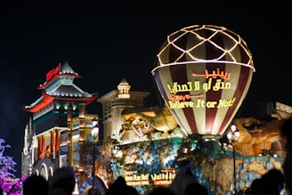 a large lit up sign in front of a building with a large crowd