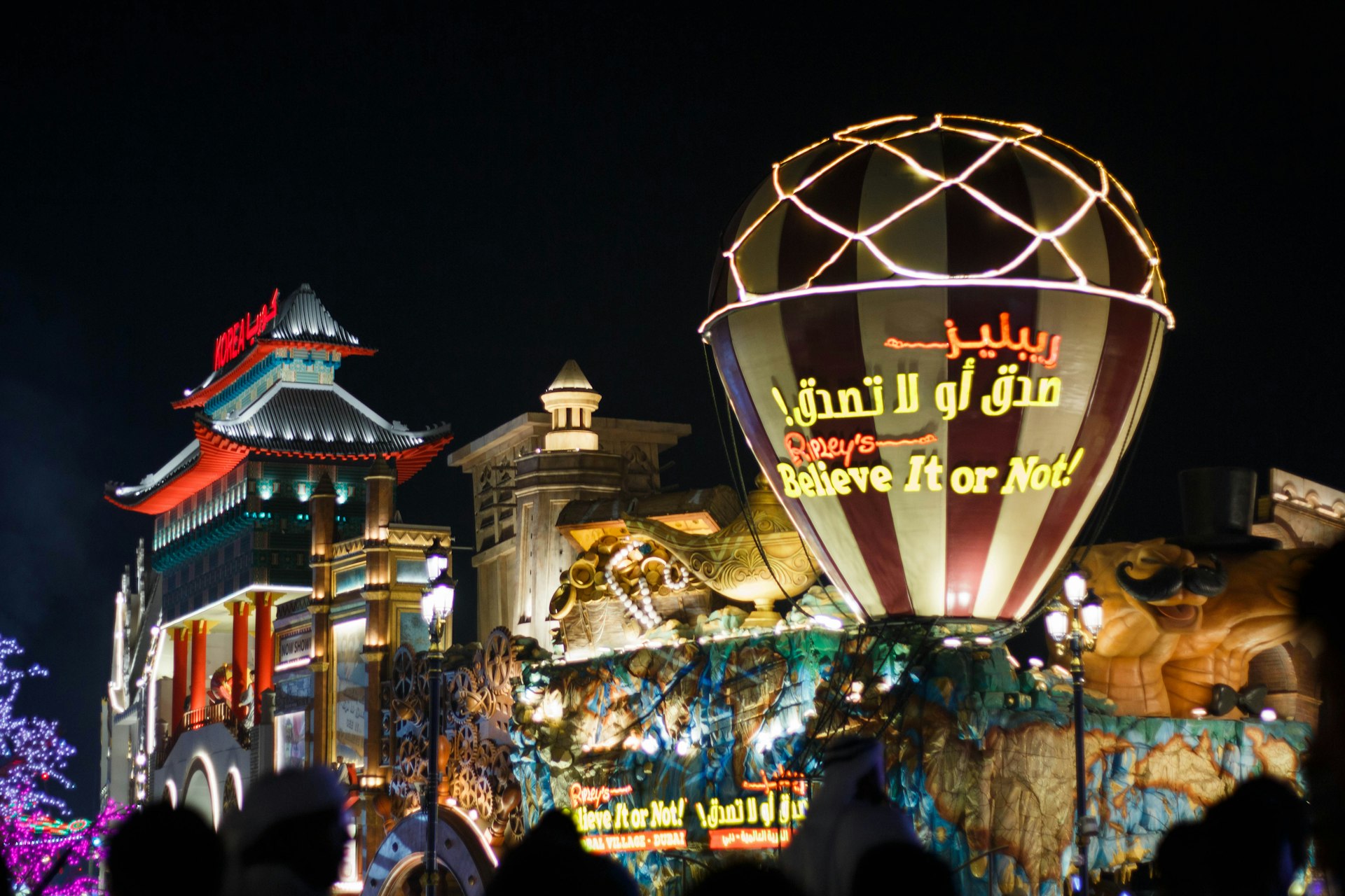 a large lit up sign in front of a building with a large crowd