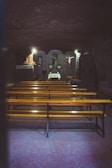 A quiet chapel interior with wooden pews and soft candlelight.