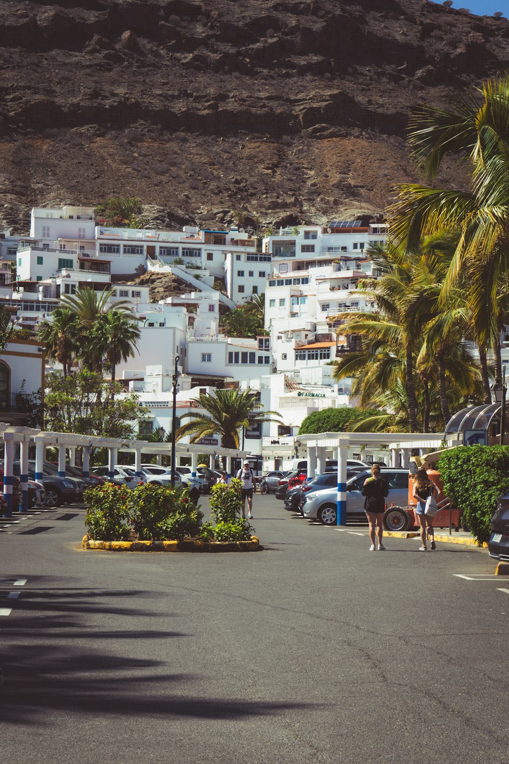 a group of people walking on a street next to a hill with buildings