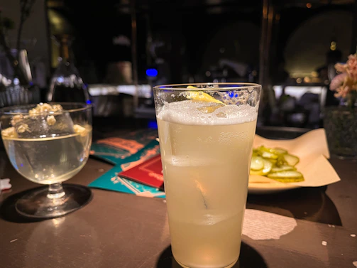 Colorful mocktail with fresh fruit garnishes and soda bubbles in a stylish cafe environment.