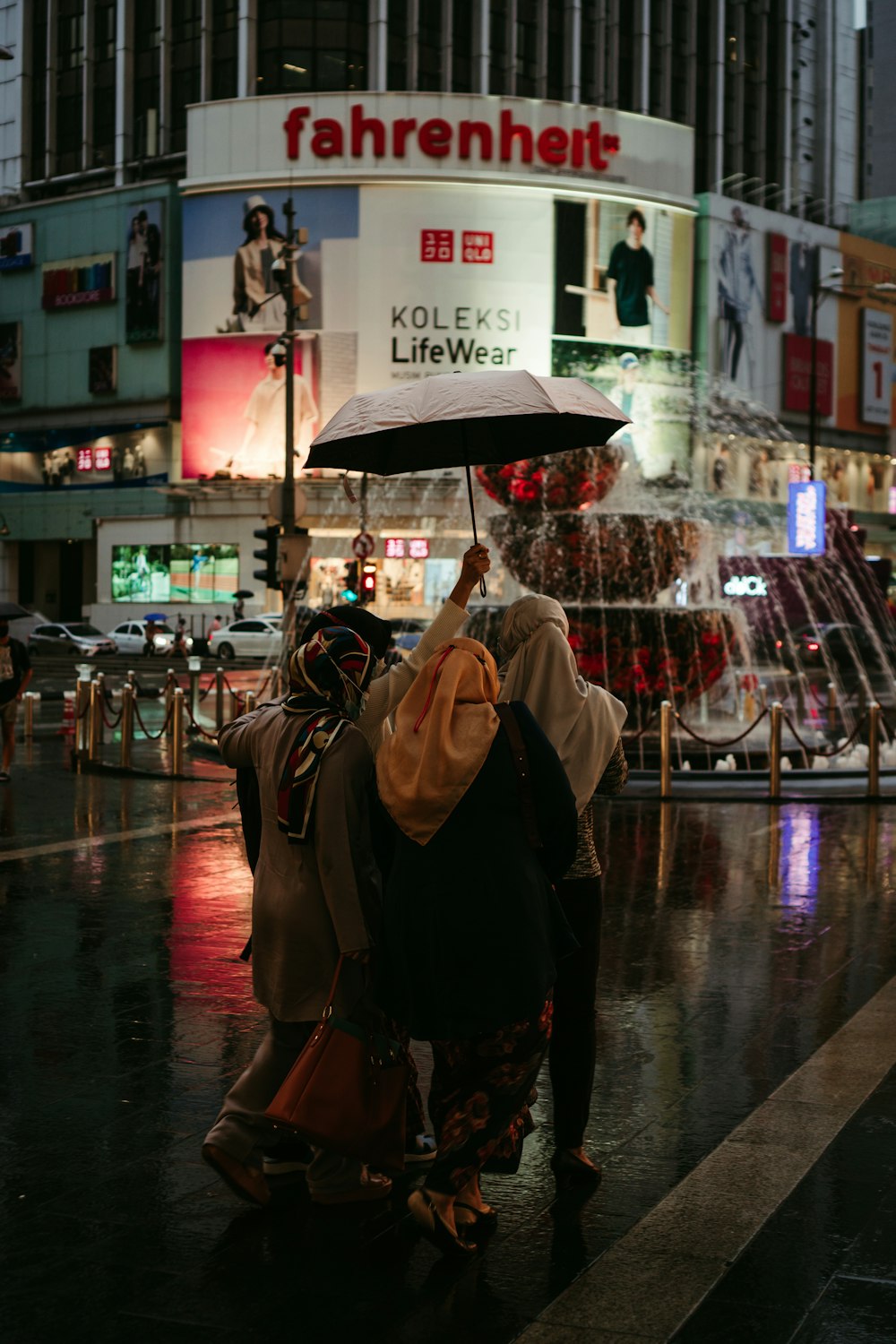 a couple of people walk under an umbrella