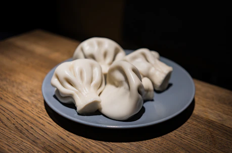 Close-up of steaming hot momos arranged on a rustic wooden platter.