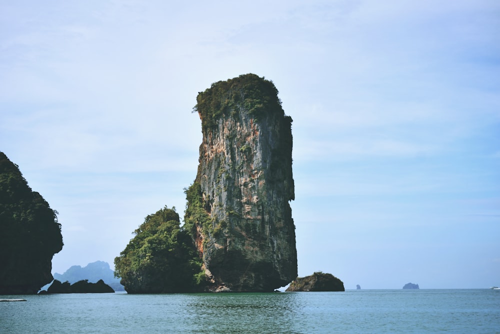a group of large rocks in the water with Ko Poda in the background
