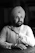 a person with a beard and a white hat sitting at a desk