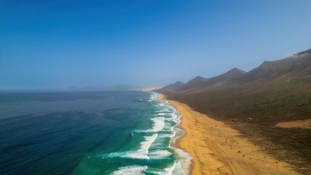 a beach with a body of water and hills in the background