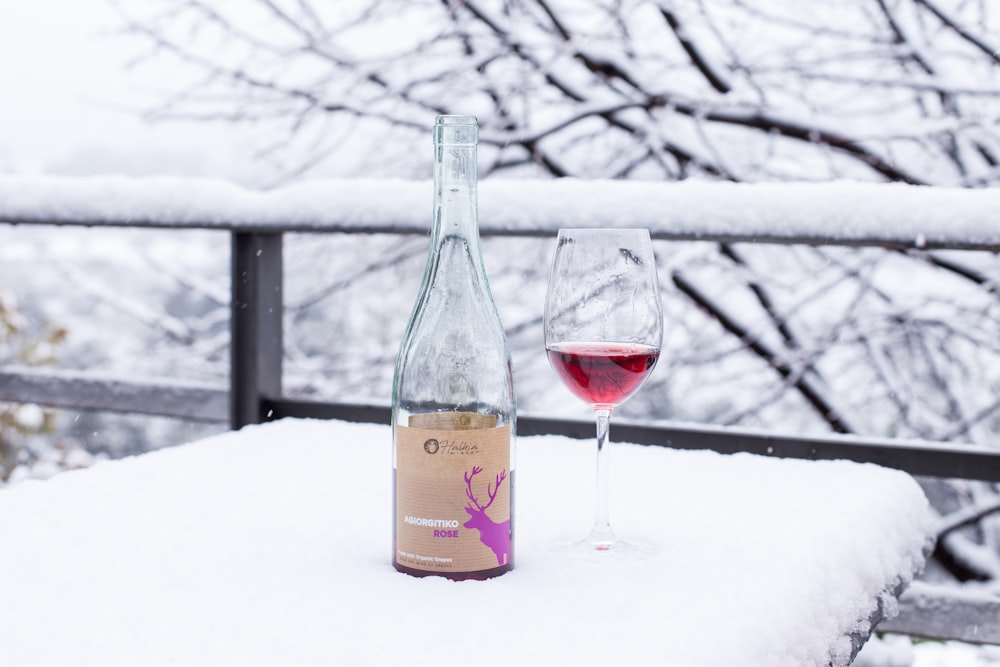 a bottle of wine and a glass of wine on a snowy day