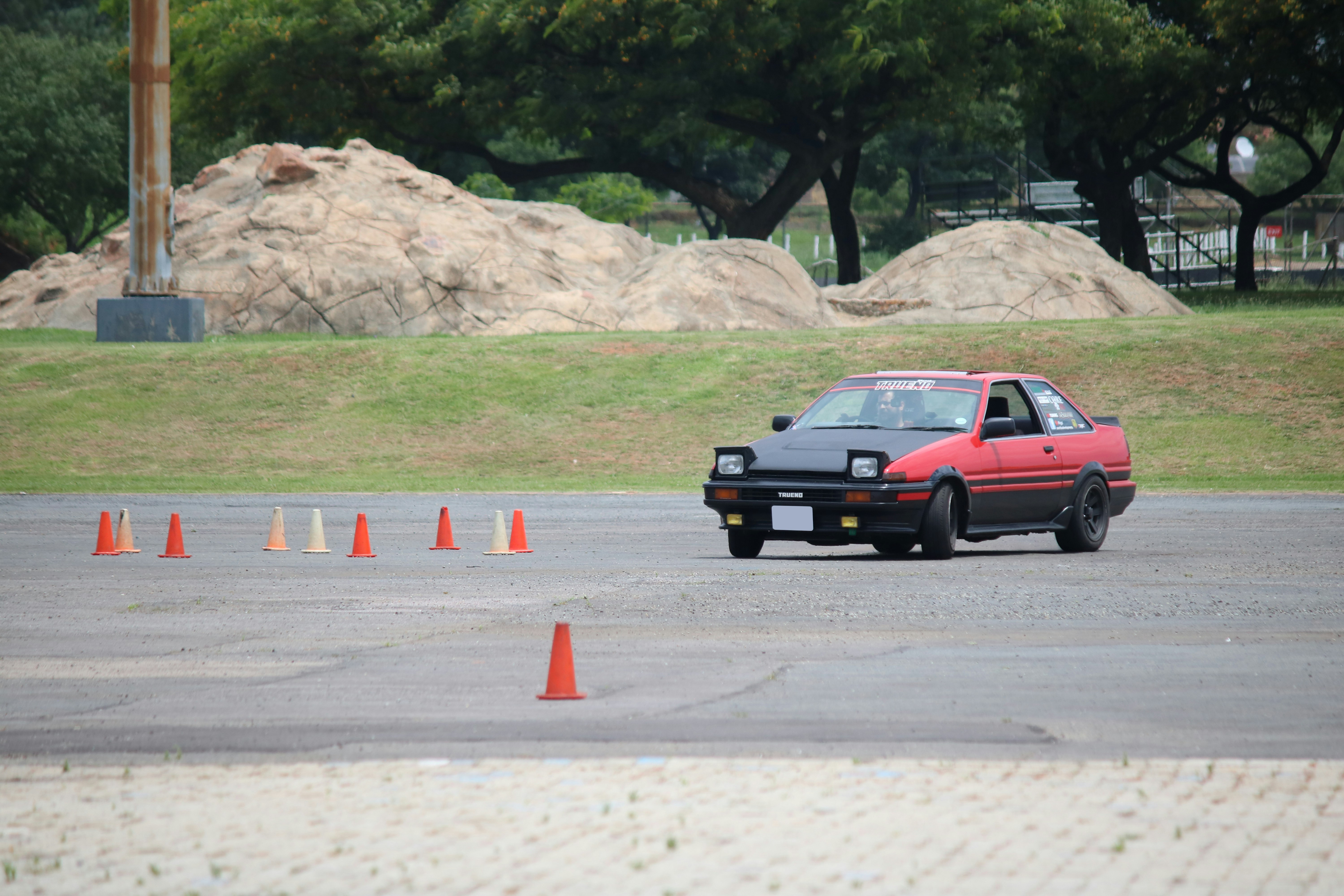 Ein rotes Auto, das um einen orange-weißen Leitkegel fährt