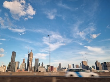 Corporate truck on highway with city skyline in the background under clear blue sky.
