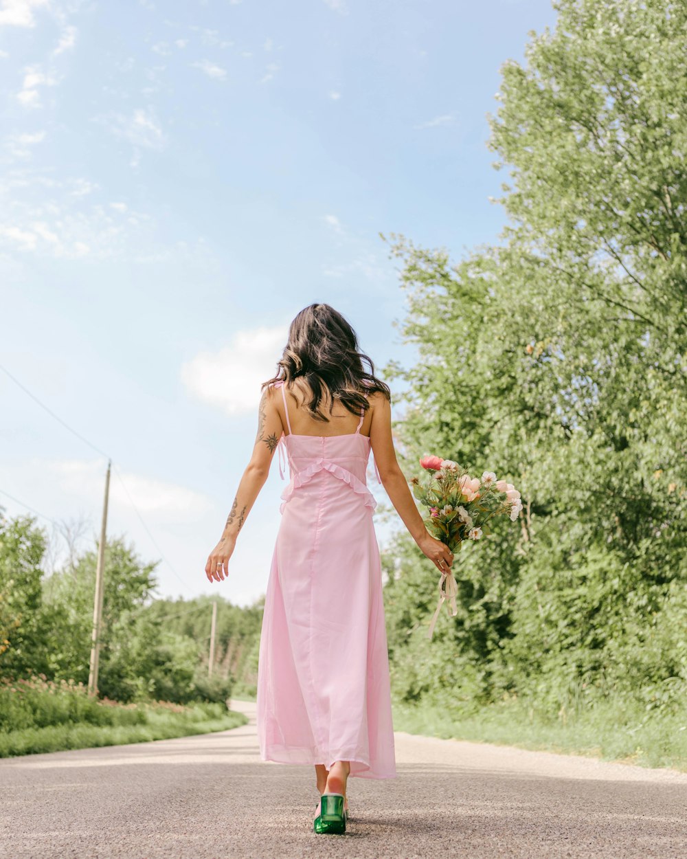 a person in a pink dress walking down a road