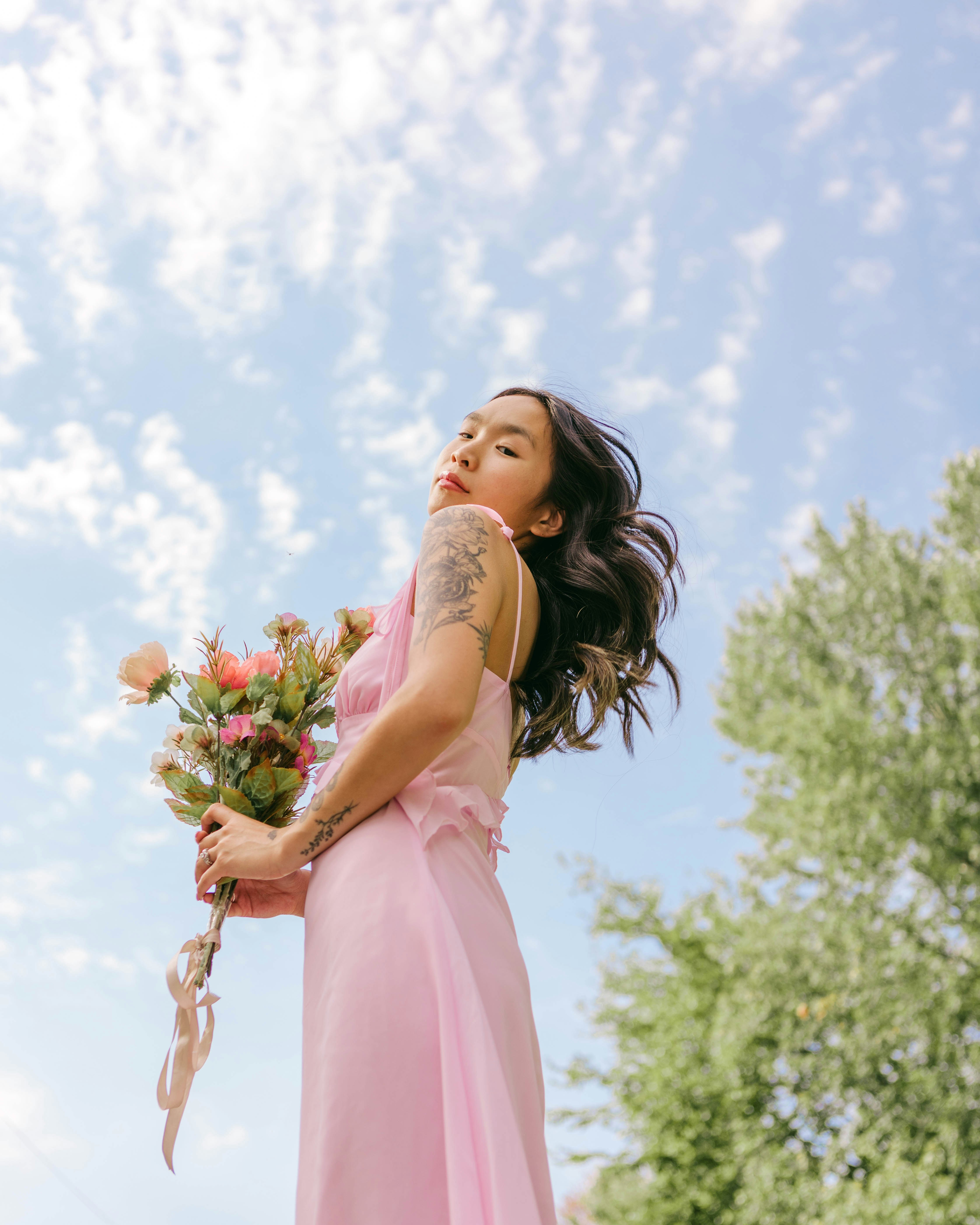 A woman in a pink dress holding flowers photo – Free Flower Image on ...