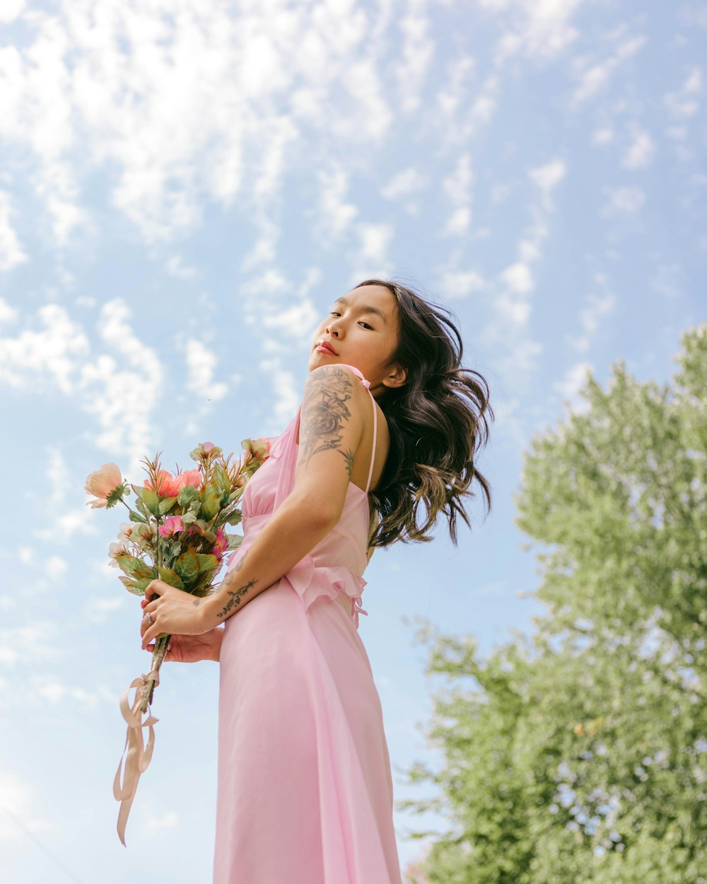 a woman in a pink dress holding flowers