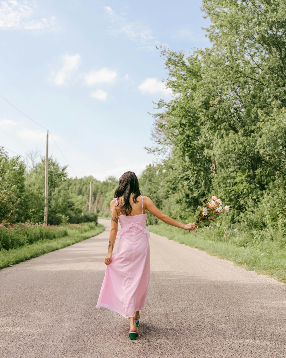 a person in a pink dress walking down a road