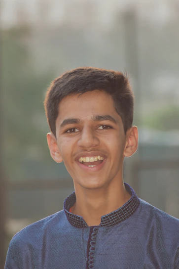 A smiling Pranav outdoors, looking energetic and healthy, with a backdrop of Baroda cityscape.