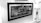 Black and white image showing a framed artwork or poster with the text 'GIRLS CAN DO ANYTHING'. The frame is positioned inside a display case or a storefront. To the right of the frame, there are glass shelves displaying various small figurines and art pieces. The background and surroundings are well-lit.