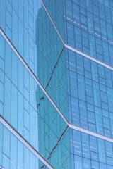 Close-up of a sleek architectural glass panel reflecting Utah's mountain skyline.