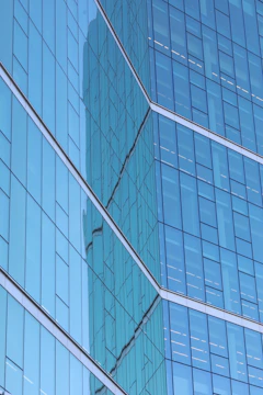 Close-up of a sleek architectural glass panel reflecting Utah's mountain skyline.