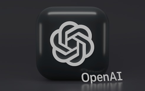 A 3D-style logo with a geometric design is prominently displayed on a dark, rounded square background. Below the logo, the word 'OpenAI' is written in a sleek, modern font.