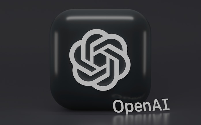A 3D-style logo with a geometric design is prominently displayed on a dark, rounded square background. Below the logo, the word 'OpenAI' is written in a sleek, modern font.
