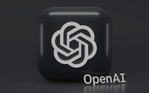 A 3D-style logo with a geometric design is prominently displayed on a dark, rounded square background. Below the logo, the word 'OpenAI' is written in a sleek, modern font.