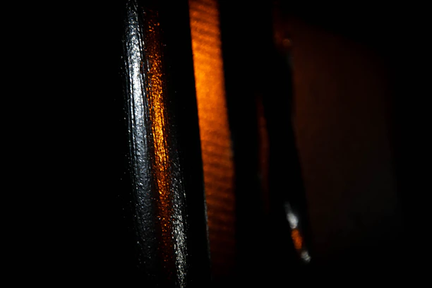 Close-up of a sleek black surface with warm ochre light reflections creating a modern artistic vibe.