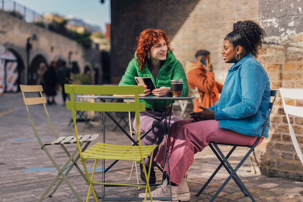 a couple of women sitting at a table outside