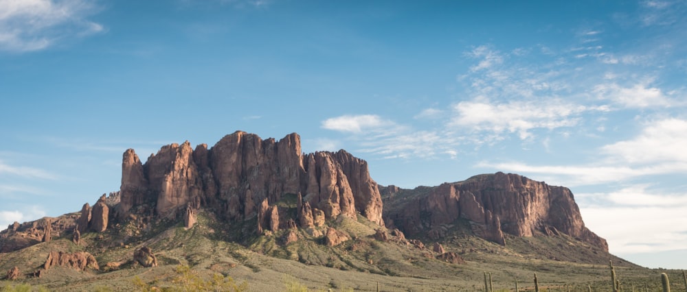 a rocky mountain with a blue sky with Superstition Mountains in the background