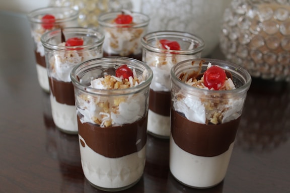 Close-up of assorted creamy mousse desserts in glass cups on a wooden table