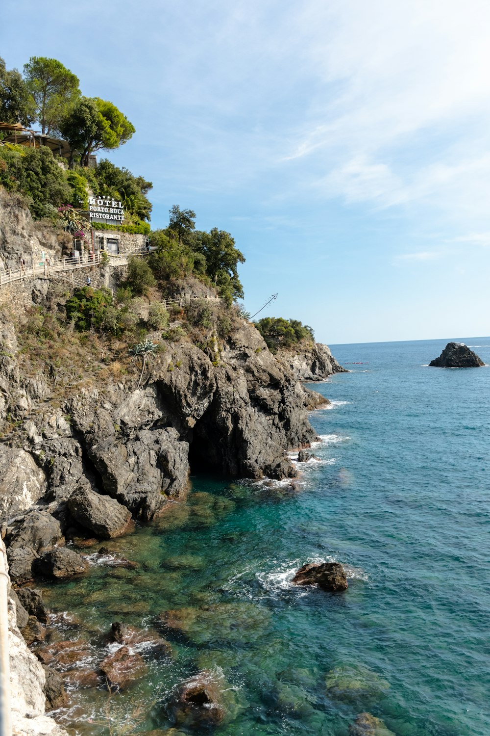 a cliff side with a building on it and a body of water below