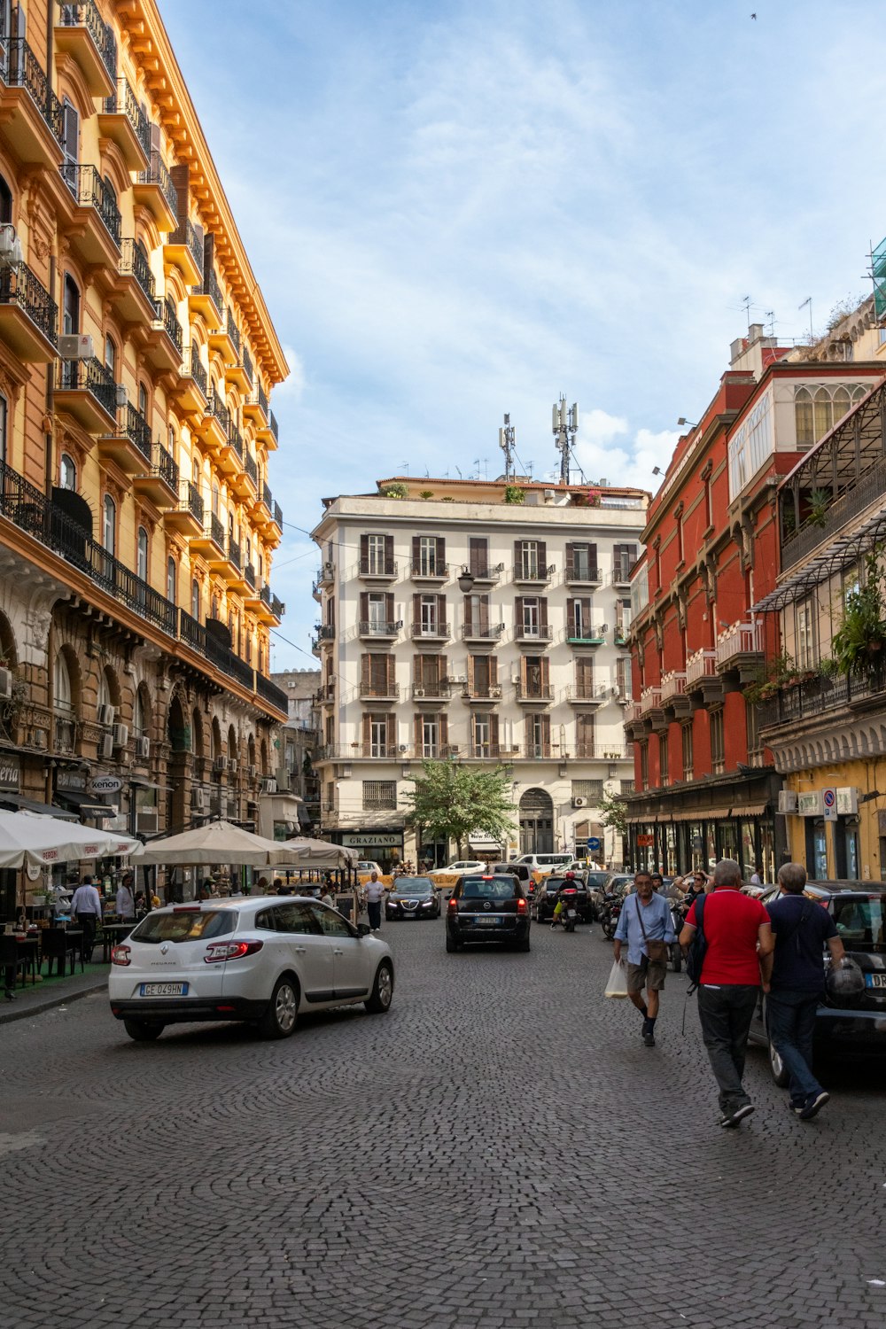 a street with cars and people on it with buildings in the back