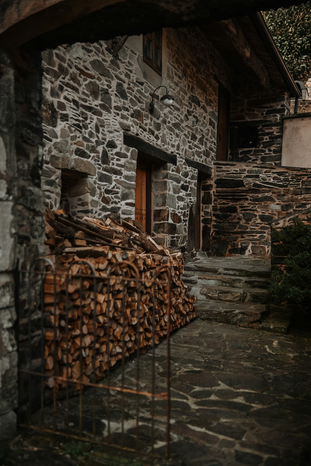 a stone building with a large pile of wood in front of it