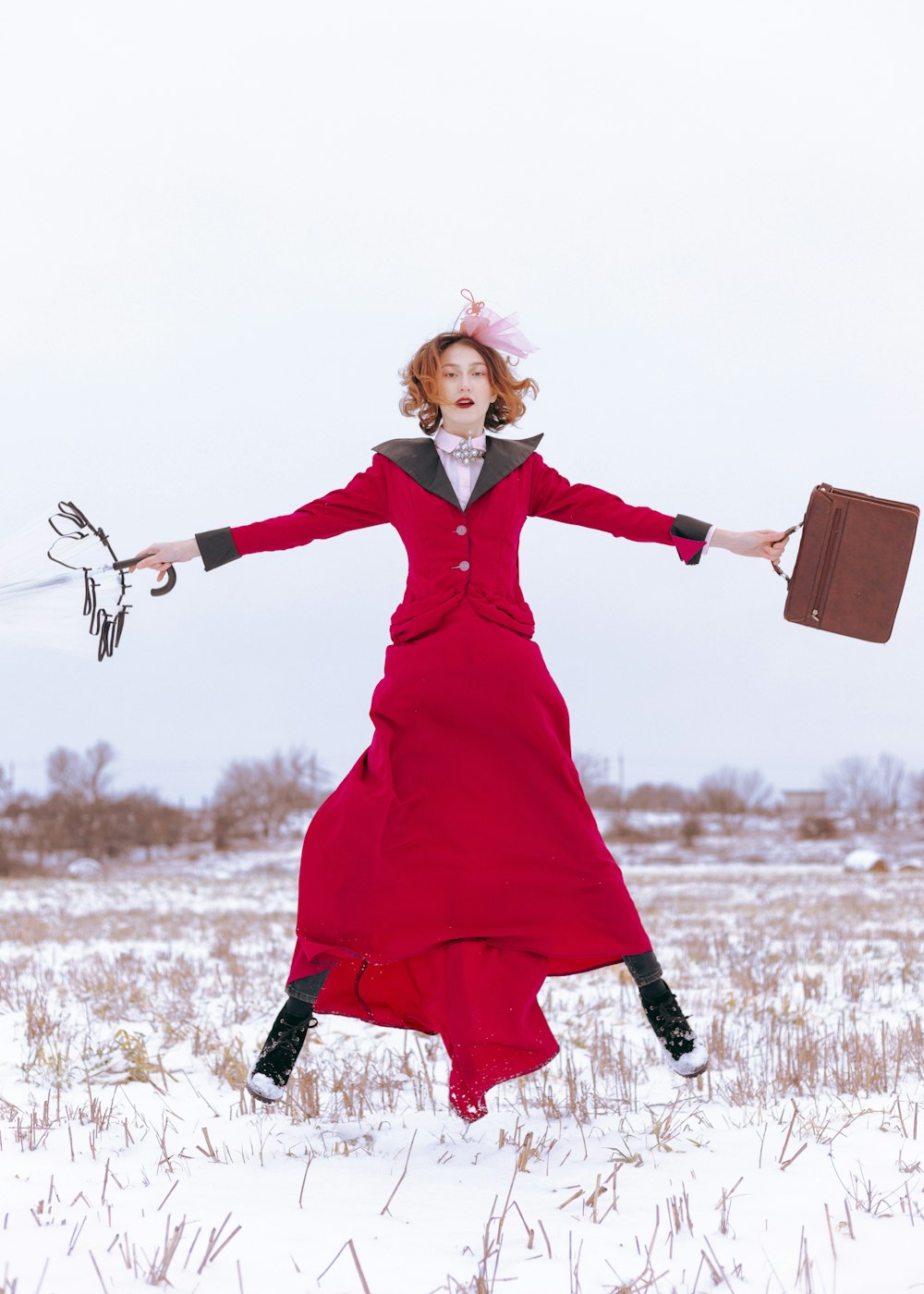a person in a red dress holding a box in a snowy field