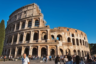 a large stone building with many arches with Colosseum in the background