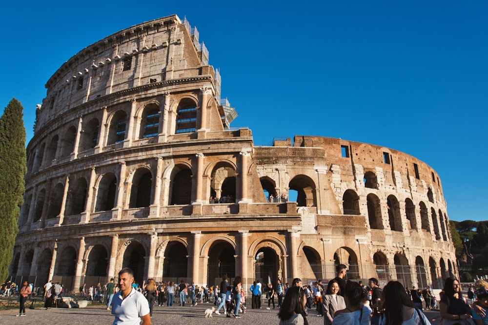 un gran edificio de piedra con muchos arcos con el Coliseo al fondo