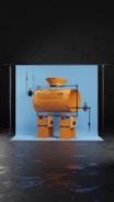 A whimsical robot-like figure constructed from industrial materials, featuring a cylindrical body and a funnel-shaped head. The structure is set against a light blue backdrop, supported by a stand on a dark floor.