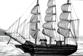 Close-up of a sleek 3D printed RC sailing yacht model on a wooden table with design sketches in the background