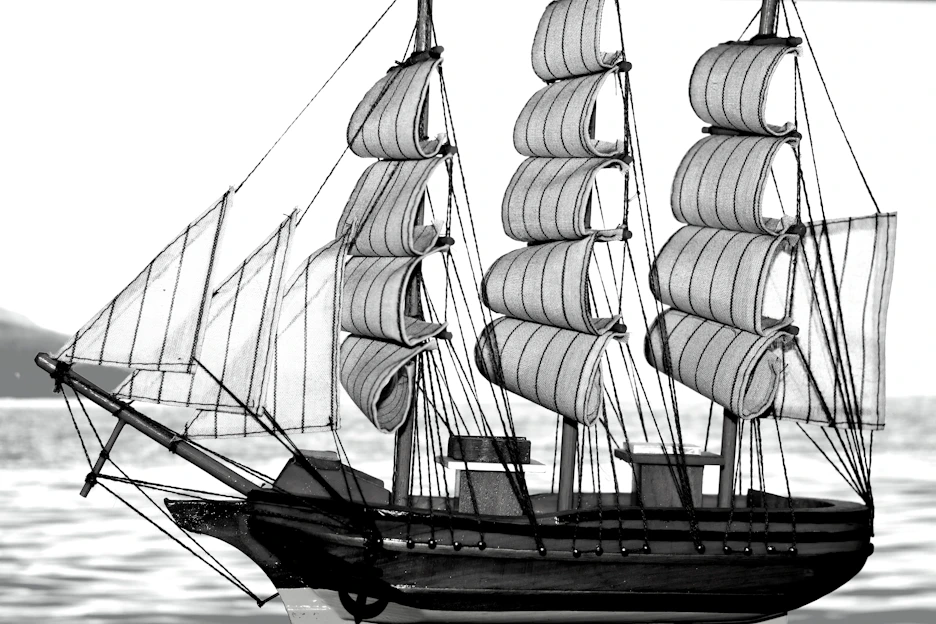 Close-up of a sleek 3D printed RC sailing yacht model on a wooden table with design sketches in the background