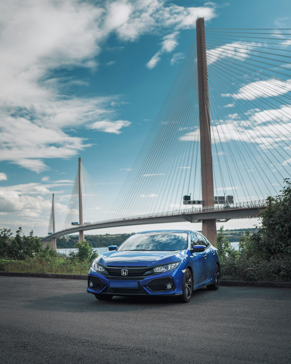 a blue car parked in front of a bridge