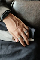 A wrist adorned with a minimalist kamariband, set against a soft white background.