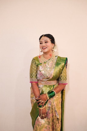 Smiling woman in traditional Indian attire working on a laptop at home.